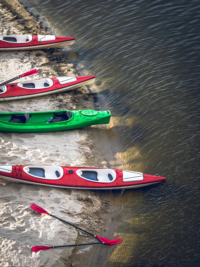 Kayaks drawn up on the sandy riverbank, seen from above